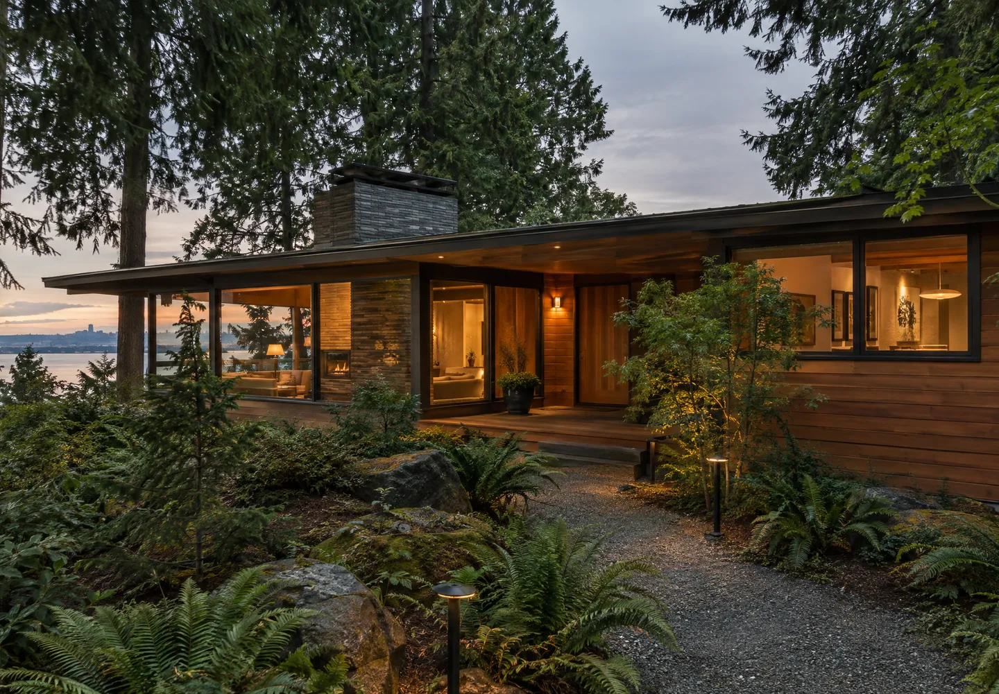Mid-century modern home with cedar siding and a fir-lined garden at dusk